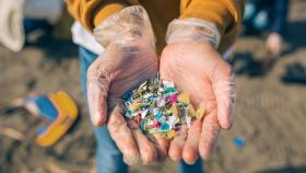 Imagen de unas manos sosteniendo microplásticos en la recogida de residuos de una playa.