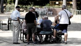 Varios pensionistas juegan al dominó en un parque de Madrid.