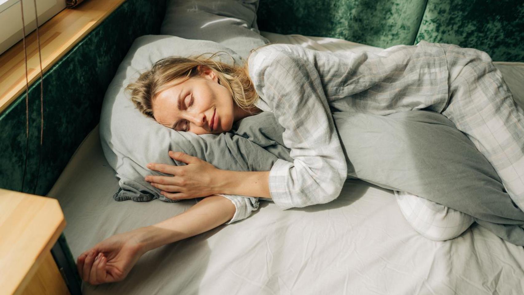 Mujer durmiendo abrazada a su almohada.