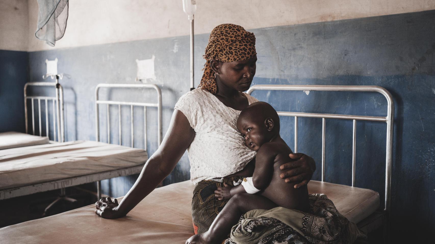 Una madre mozambiqueña abraza a su hijo que padece malaria en un viaje con Manos Unidas.