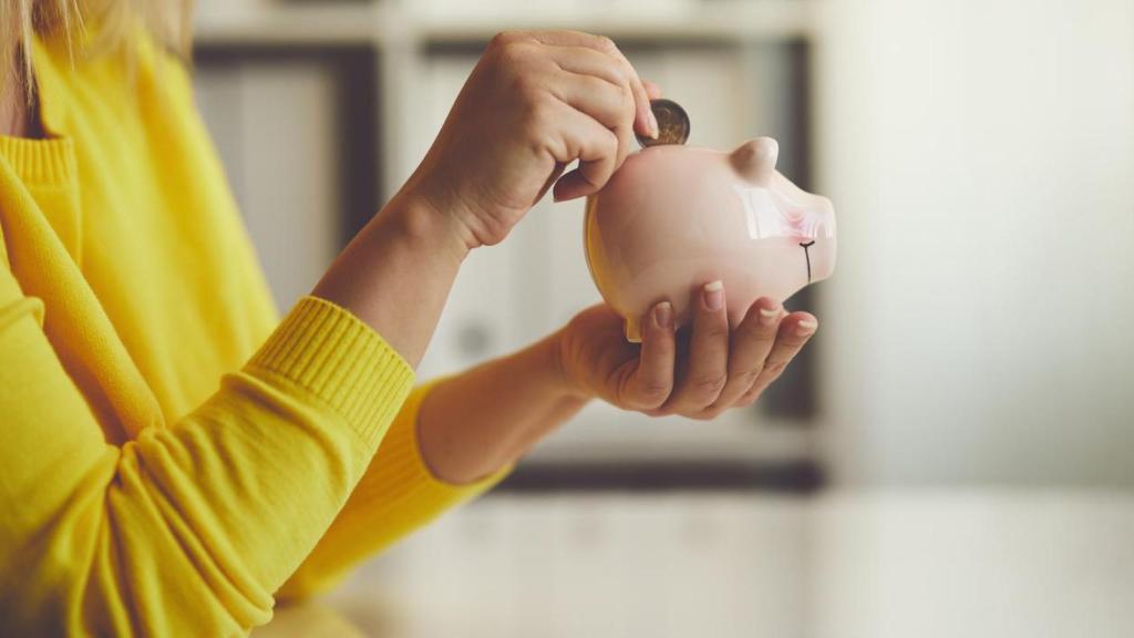 Mujer echando dinero en una hucha.