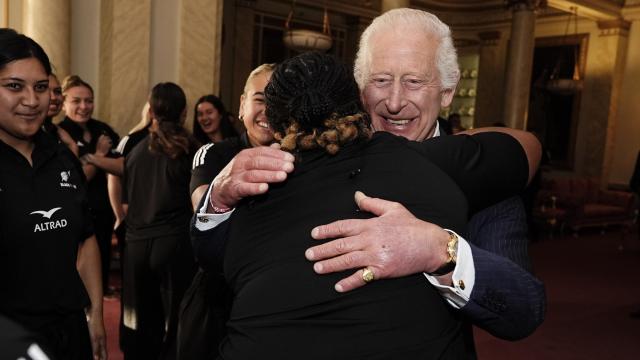 El rey Carlos III abrazando a una de las jugadoras de rugby del equipo de Nueva Zelanda.