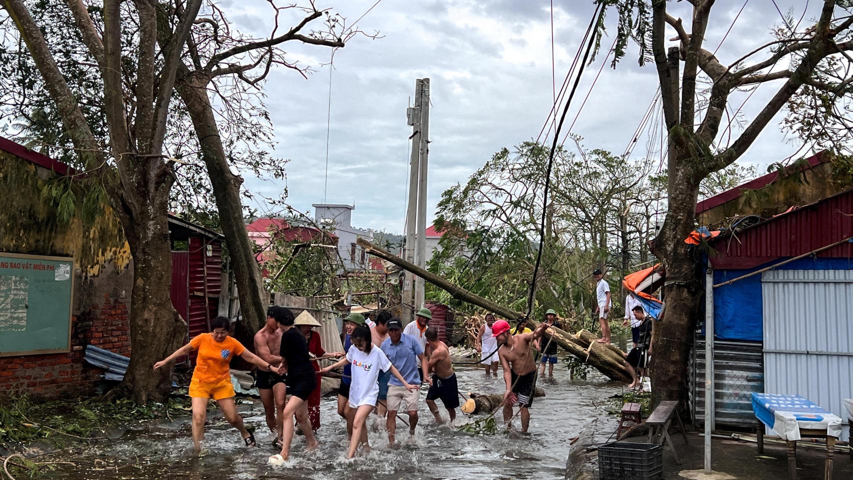 Varias personas utilizan cuerdas para retirar los árboles caídos en la localidad de Hai Phong, Vietnam.