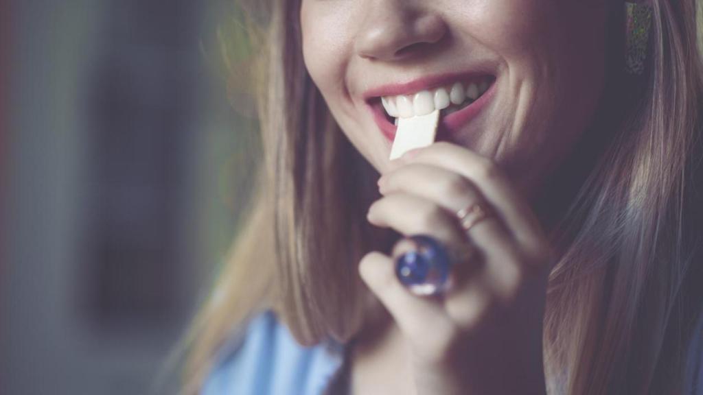 Mujer metiéndose un chicle en la boca.