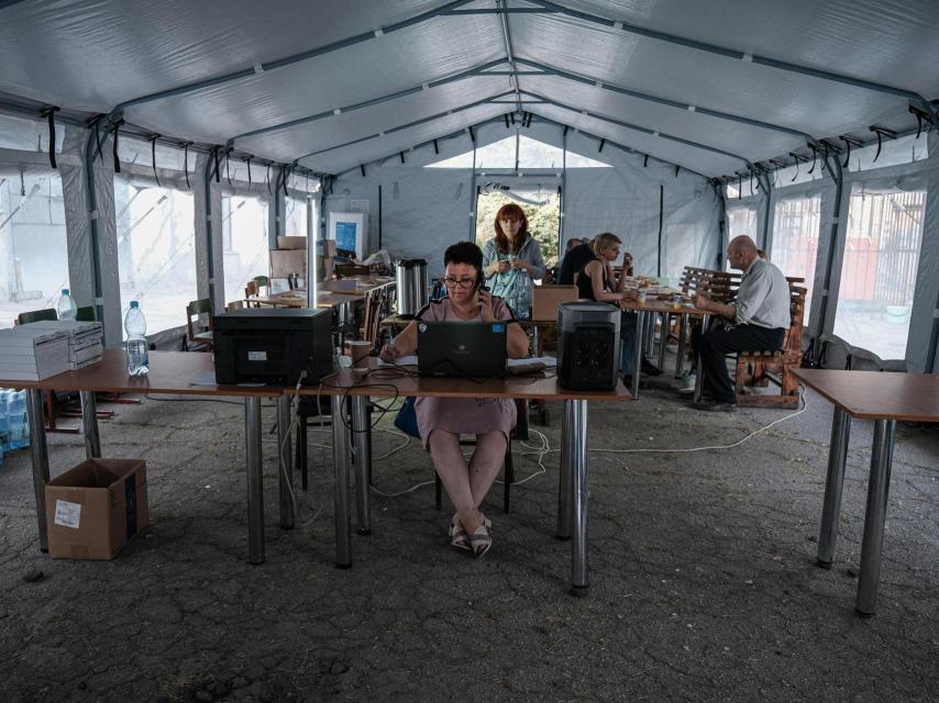 Volunteers register evacuees from Donbas in a tent that Caritas has set up next to the transit centre.