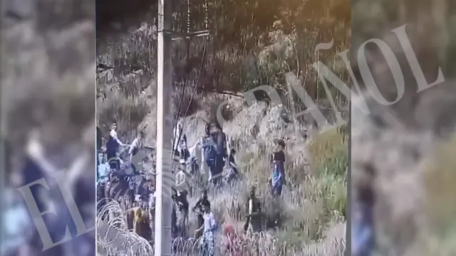 Decenas de migrantes lanzan piedras junto a la valla de Ceuta.