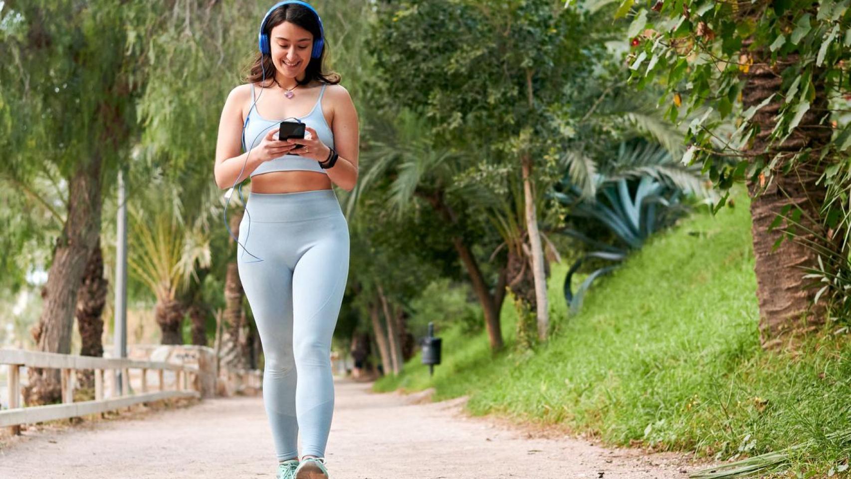 Mujer con ropa deportiva caminando por el parque.