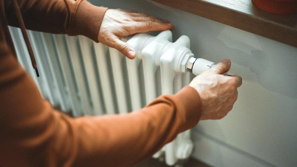 Una persona regulando la temperatura de un radiador.