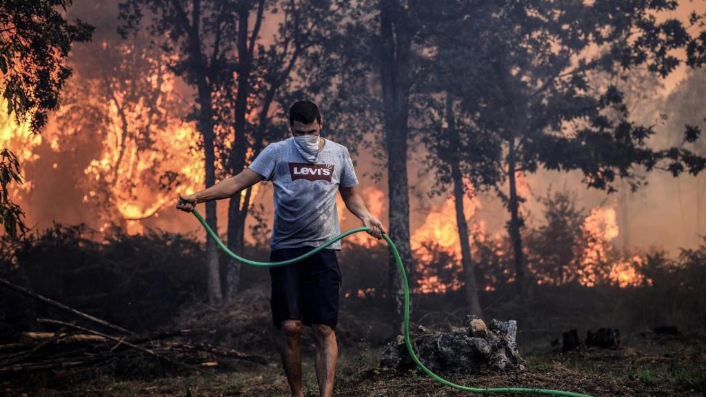 Un hombre sostiene una manguera mientras lucha contra un incendio forestal en Macinhata da Seixa, Oliveira de Azemeis.