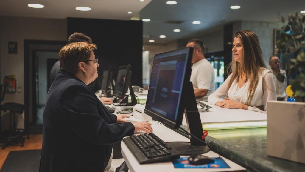 Isabel atiende a una clienta en la recepción del hotel.