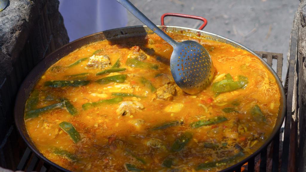 Una persona cocina una paella.