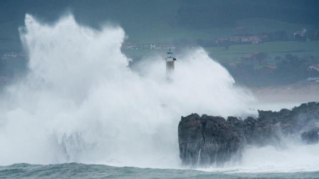 Ola gigante cubriendo a un faro en pleno temporal.