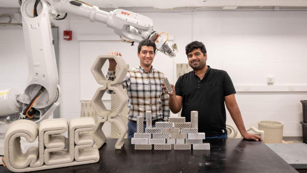 Reza Moini y Shashank Gupta junto al brazo robótico de impresión 3D y sus materiales de cemento