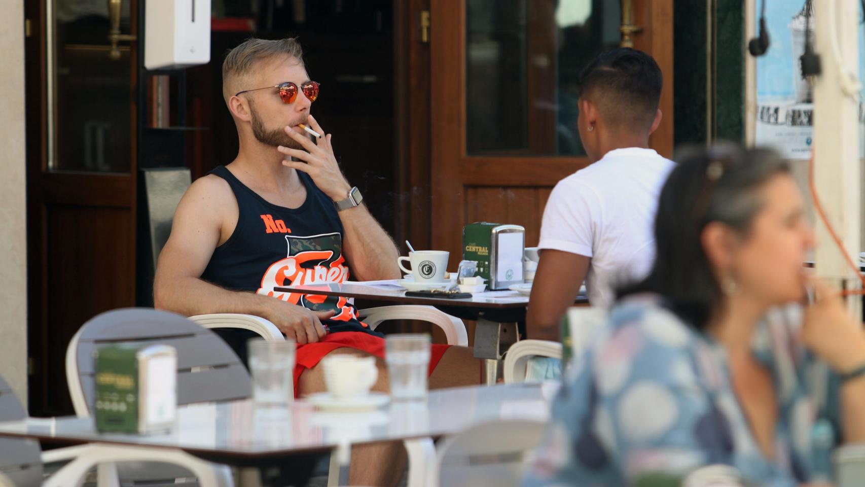 Una persona fumando en una terraza.