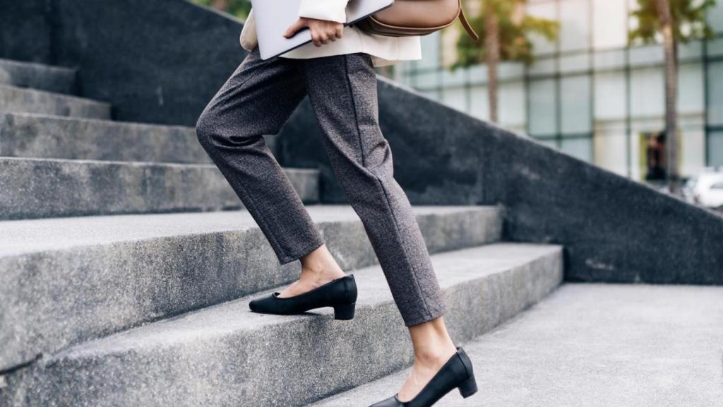 Mujer con portátil en la mano subiendo escaleras.