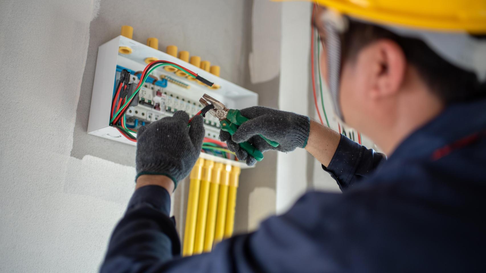 Un electricista cablea una casa.