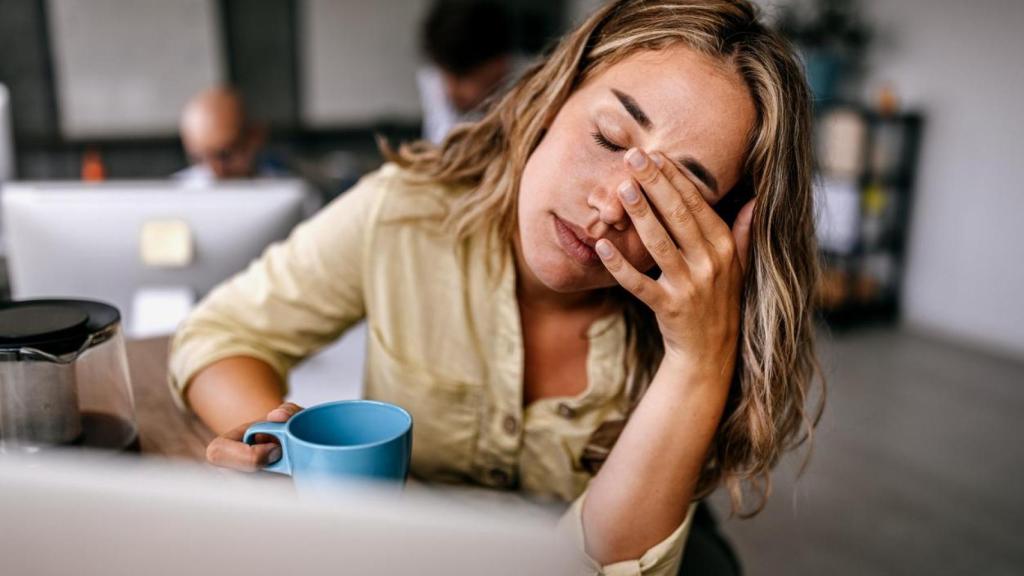 Mujer con aspecto cansado con una taza en la mano.