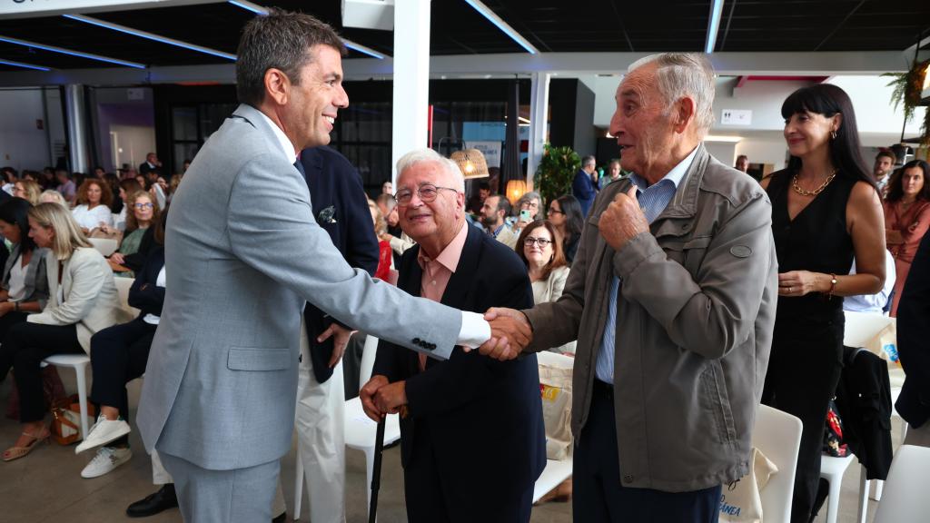 Carlos Mazón, en la presentación del nuevo programa de viajes para personas mayores Viaja+65, tiende la mano a uno de ellos. EE