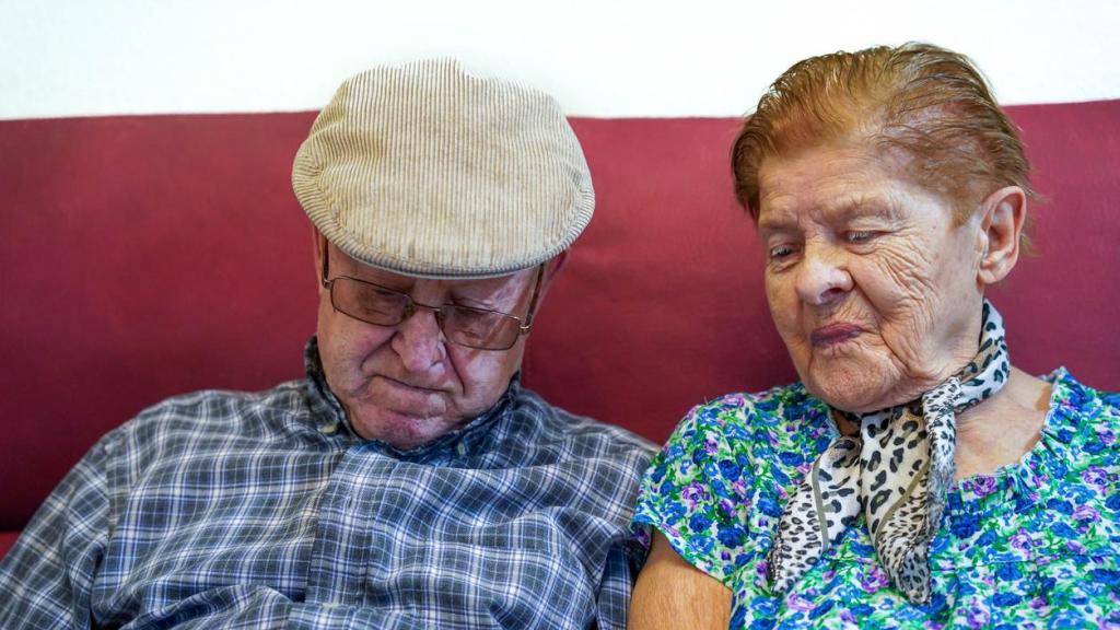 Pareja de ancianos juntos en un sofá.