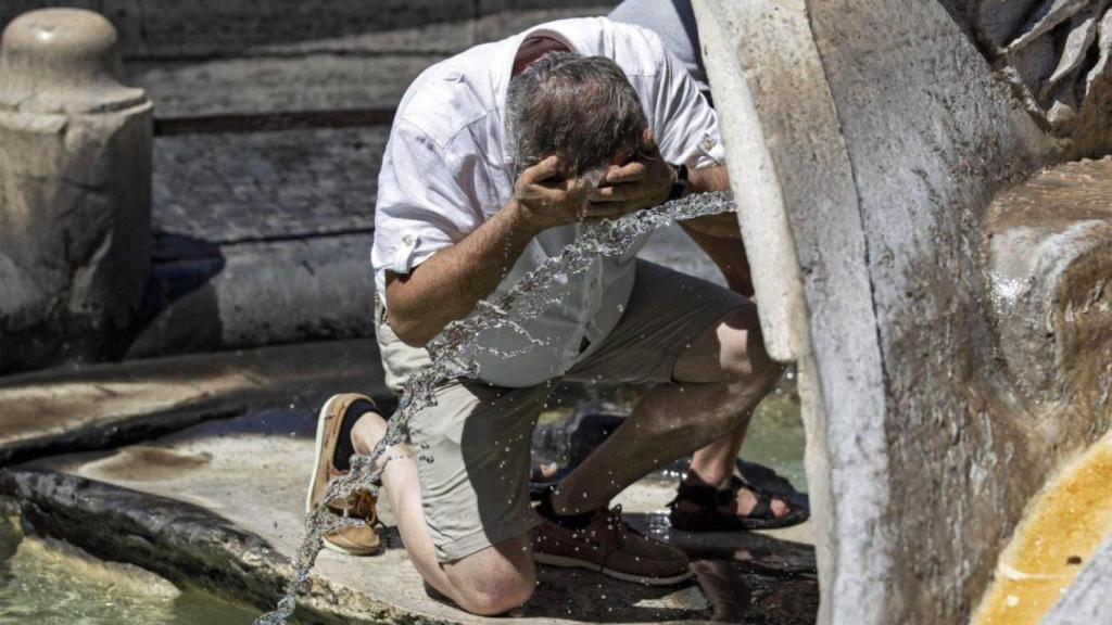 Un turista se refresca durante un día de calor de este verano en Sevilla.