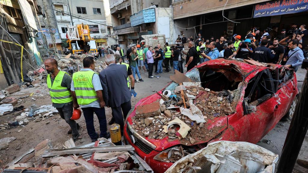 Varias personas este martes junto a un automóvil destruido en el lugar de un ataque israelí en los suburbios del sur de Beirut.