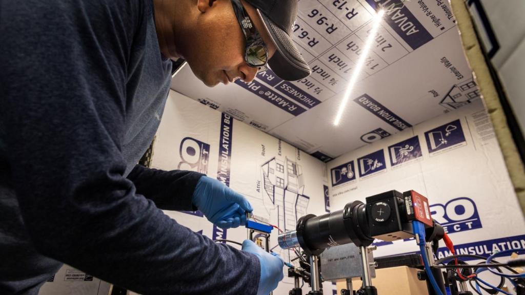 Raju Lampande colocando un OLED frente a un sistema de imágenes de microscopio.