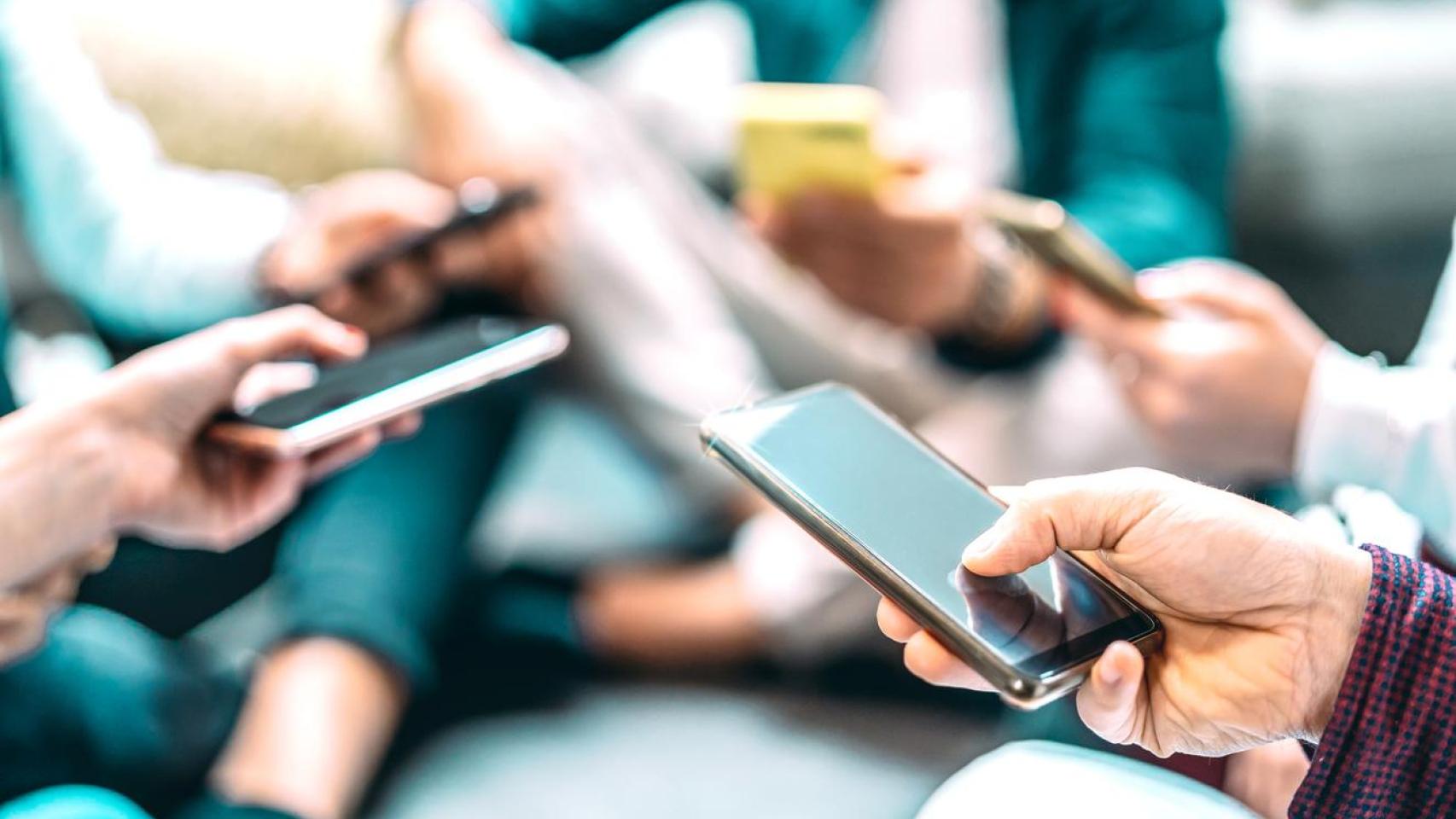 Grupo de personas con teléfonos móviles.