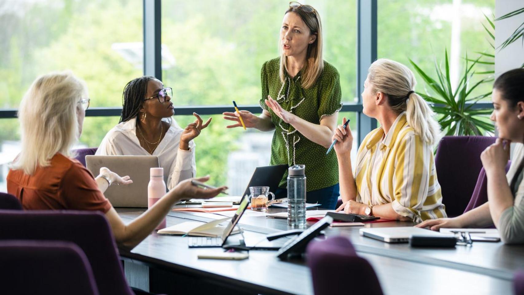 Grupo de mujeres debatiendo sobre cuestiones laborales en un entorno de trabajo.