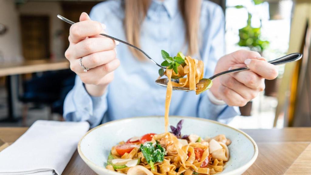 Mujer comiendo pasta en un restaurante.