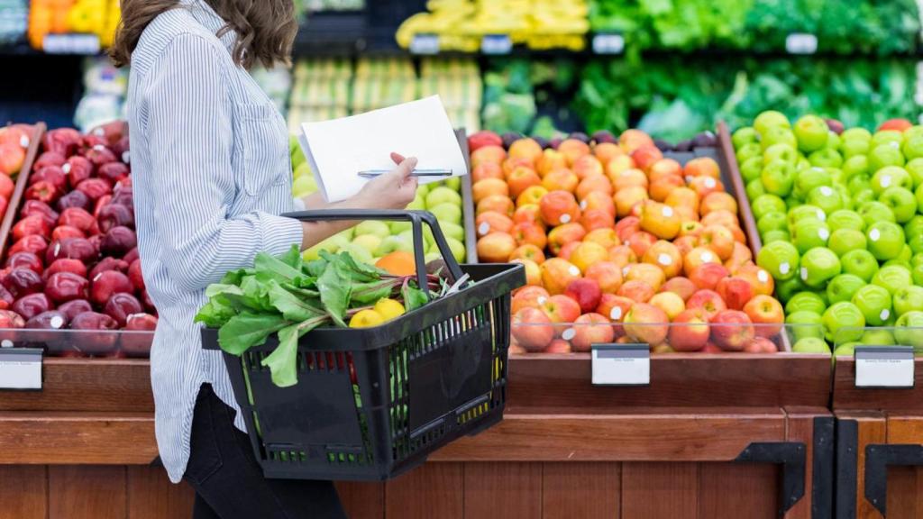 Mujer haciendo la compra en la sección de fruta y verdura de un supermercado.