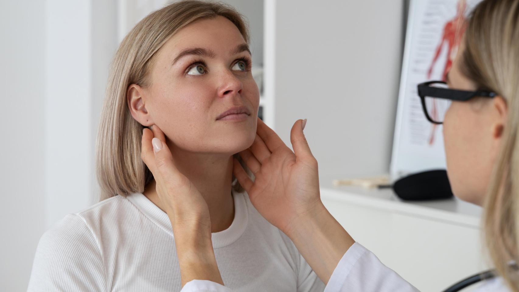 Mujer rubia en consulta médica durante exploración de garganta