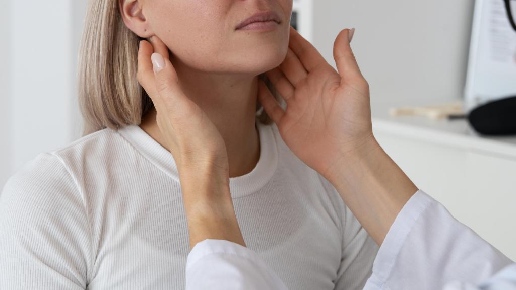 Mujer rubia en consulta médica durante exploración de garganta