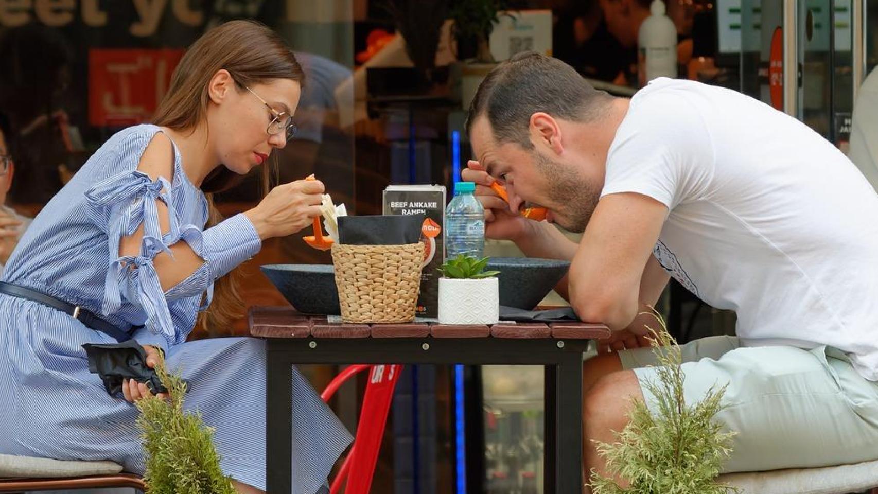 Una pareja comiendo en la terraza de un restaurante.