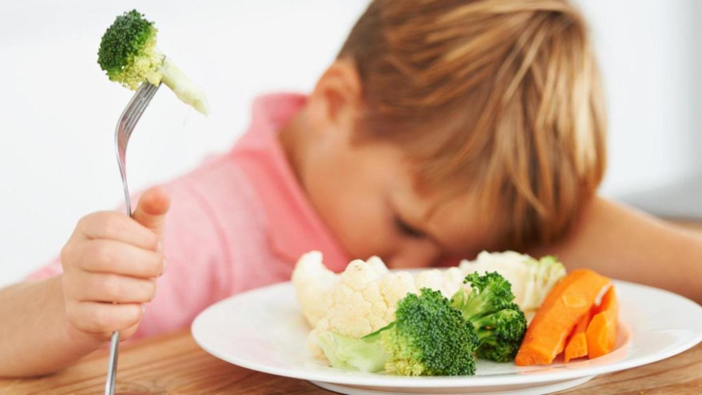 Un niño sufriendo por tener que comerse un plato de verduras.