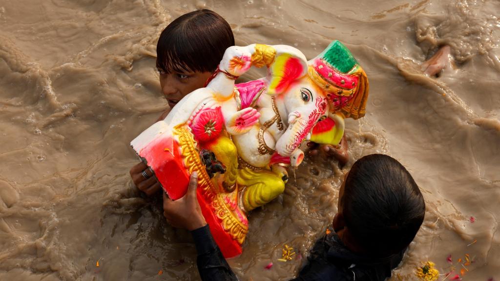 Unos niños transportan a Ganesha, el dios hindú de cabeza de elefante, en Nueva Delhi.