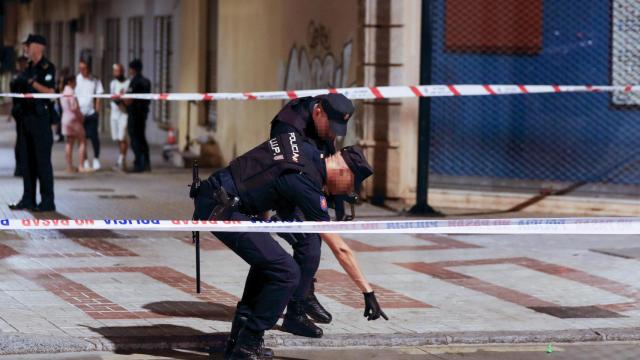 Agentes de policía señalan un charco de sangre en el lugar en el que se ha producido un tiroteo en el que varias personas han resultado heridas este sábado por la tarde en Málaga capital.