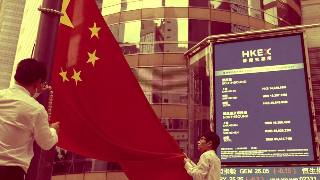 Dos trabajadores colocan una bandera de China en la entrada de la Bolsa de Shanghái.