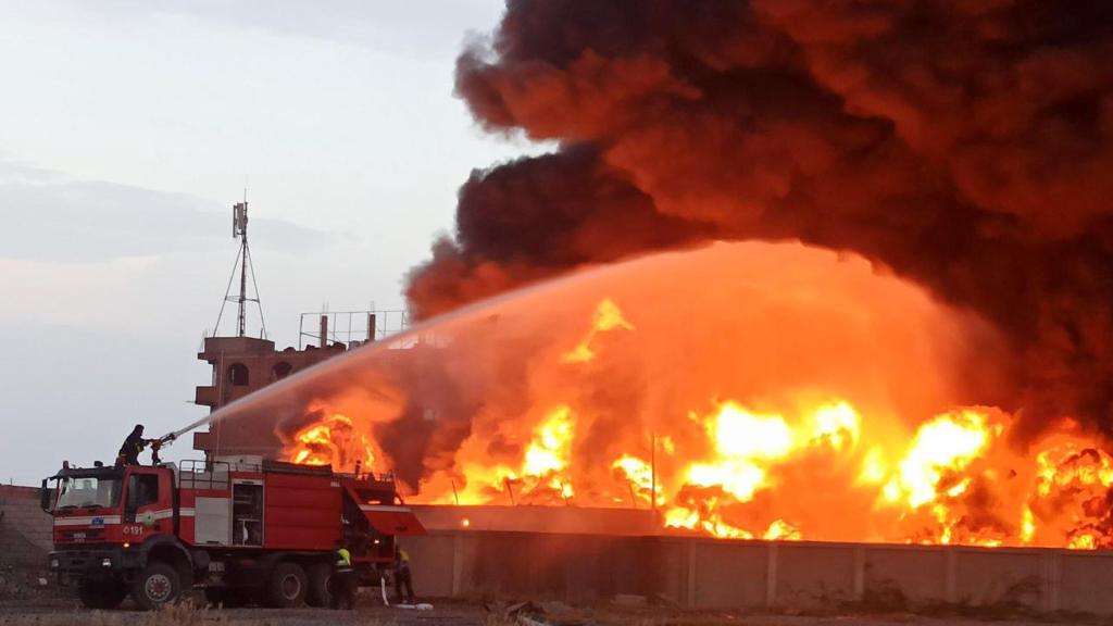 Bomberos intentan extinguir el incendio en una central eléctrica tras los ataques aéreos israelíes del domingo en la ciudad yemení de Hodeida.