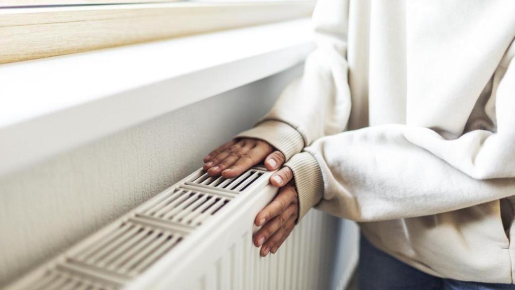 Mujer calentándose con el radiador.