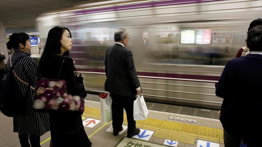 Un grupo de viajeros espera el tren en un andén de Osaka.