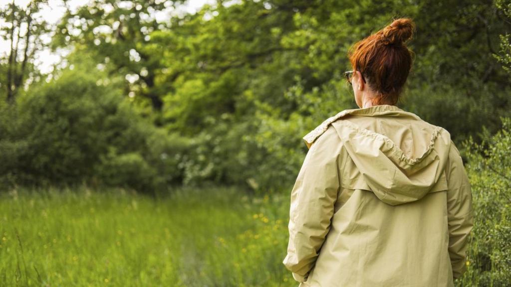 Joven de espaldas en el bosque con una parka.