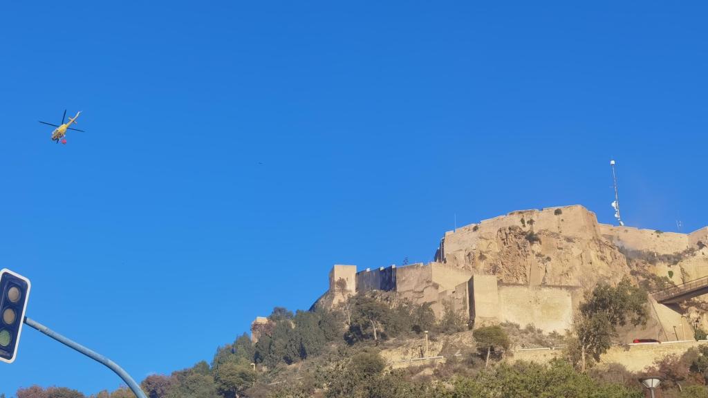 Una de las pasadas del helicóptero sobre el pequeño incendio en el muro del castillo de Santa Bárbara.