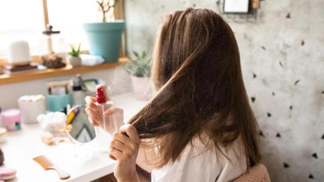 Mujer aplicándose producto en el pelo.