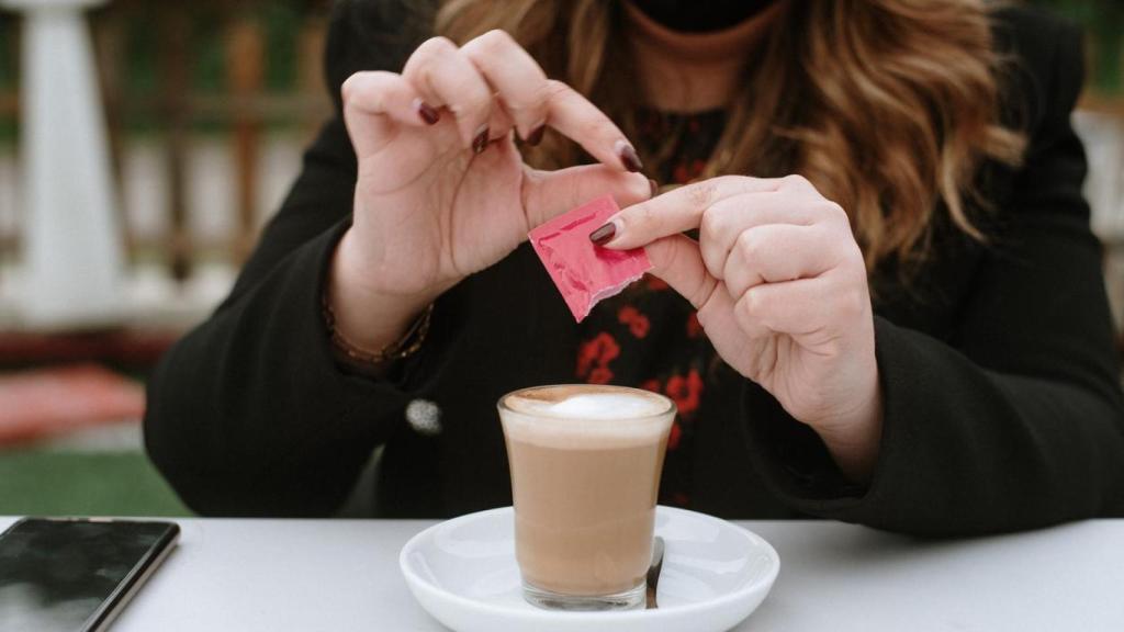 Mujer echándose azúcar en el café.