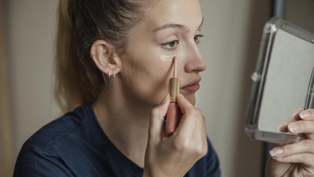 Mujer aplicándose corrector.