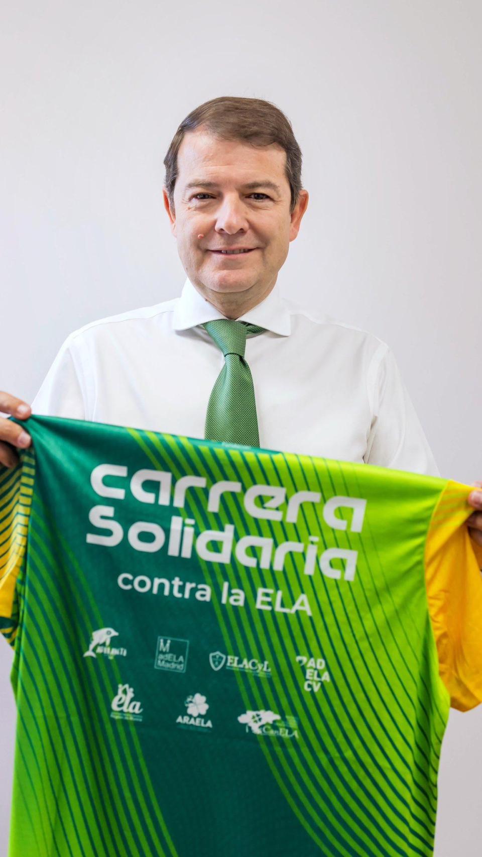 El presidente de la Junta, Alfonso Fernández Mañueco, sostiene la camiseta de la Carrera Solidaria contra la ELA