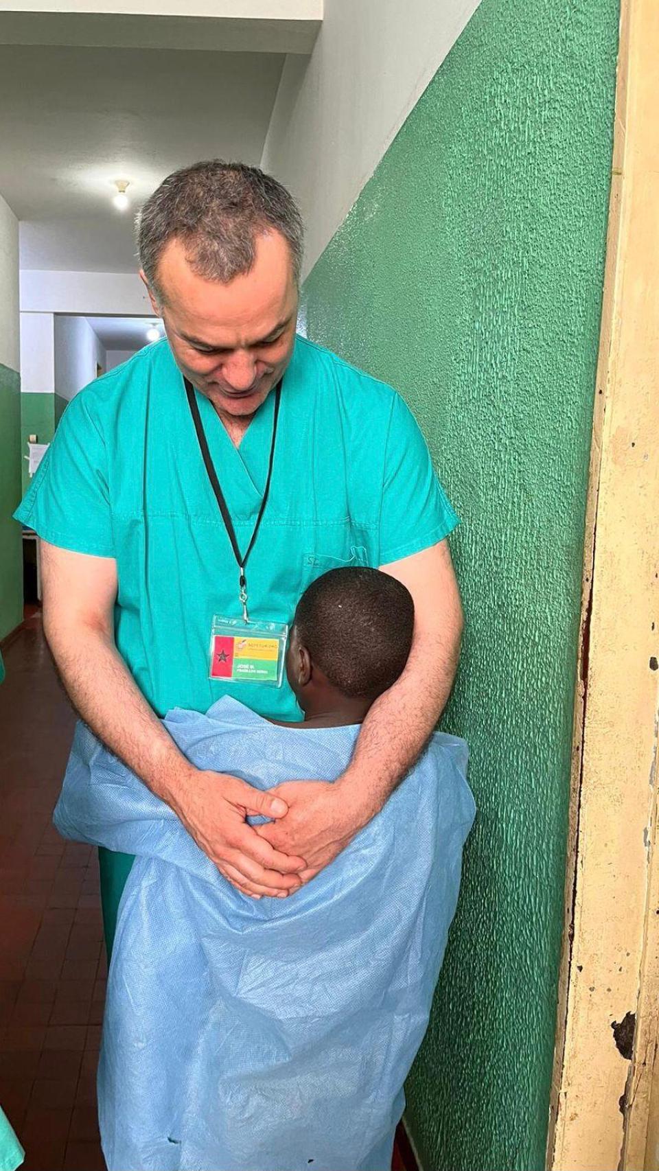 José María se abraza a un niño después de haberle atendido en Guinea-Bisáu.