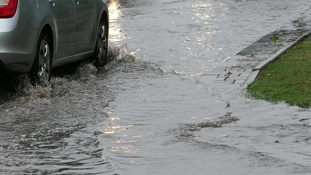 Coche circulando por una calle inundada.