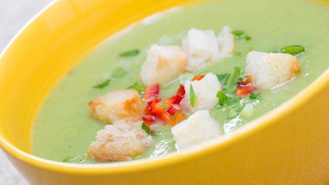 Una sopa de curry verde con cilantro, pimiento rojo y croutons