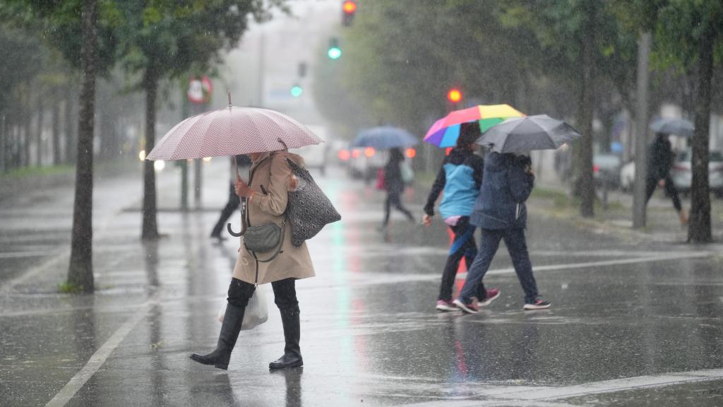 Varias personas caminan bajo la lluvia.